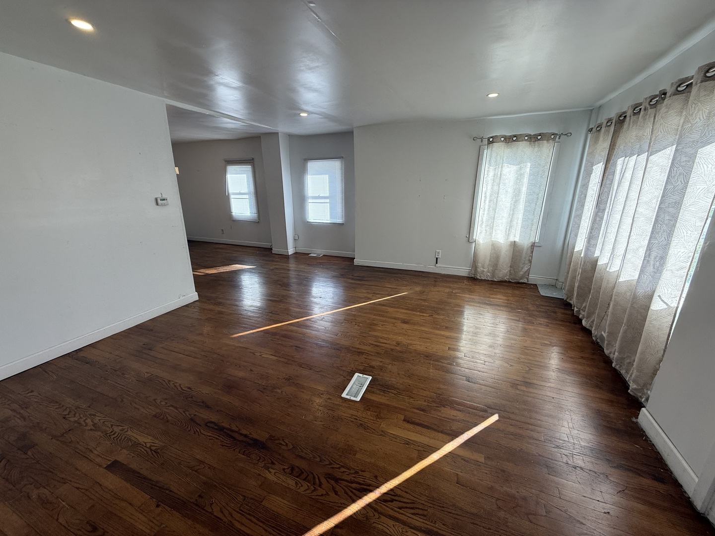 732 North Dearborn Avenue Kankakee, IL 60901 - Photo 7 of 21 an empty room with wooden floor and windows with curtains