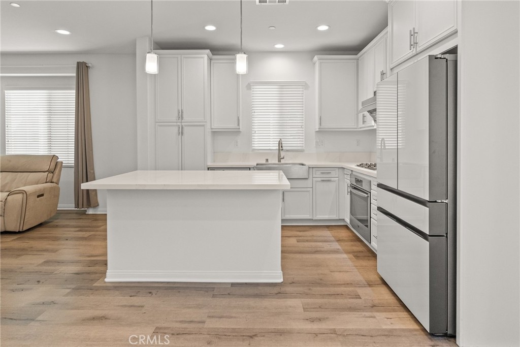 8743 Celebration Street Chino, CA 91708 - Photo 7 of 42 a white kitchen with wooden floor and stainless steel appliances