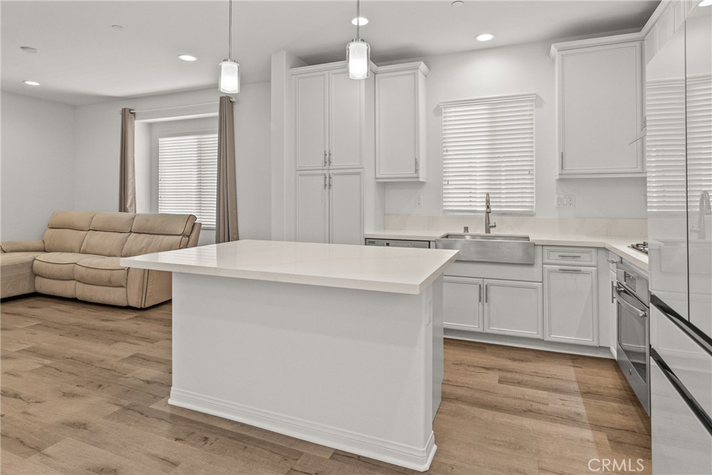 8743 Celebration Street Chino, CA 91708 - Photo 9 of 42 a large white kitchen with a sink stove and white cabinets with wooden floor