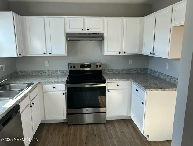 a kitchen with stainless steel appliances granite countertop white cabinets stove top oven and sink
