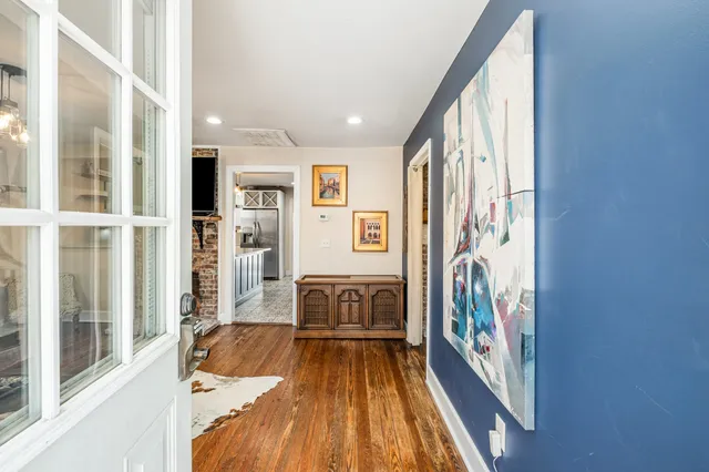 a view of a hallway to a livingroom with wooden floor and windows
