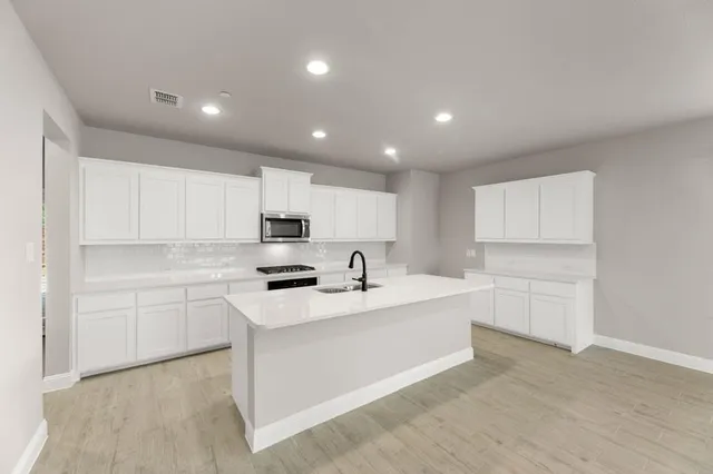 a kitchen with white cabinets appliances and sink
