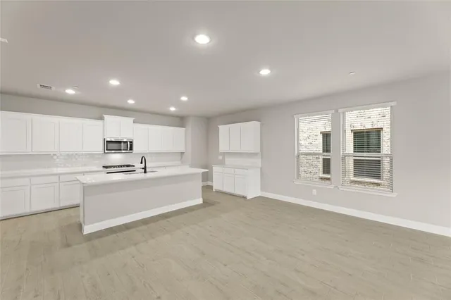 a large white kitchen with white cabinets and a refrigerator