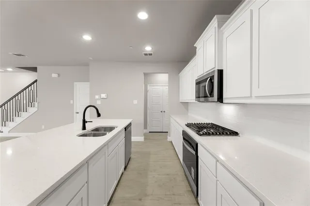 a kitchen with stainless steel appliances granite countertop a sink a stove and a refrigerator