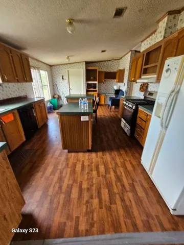 a living room with couches and kitchen view with wooden floor