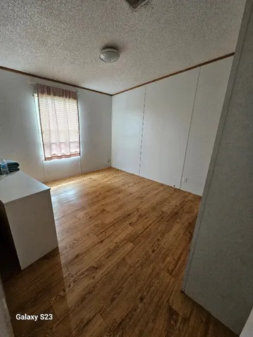 a view of empty room with window and wooden floor