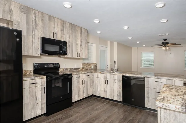 a kitchen with stainless steel appliances granite countertop a sink stove microwave and refrigerator