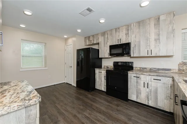 a kitchen with granite countertop a refrigerator stove top oven and sink