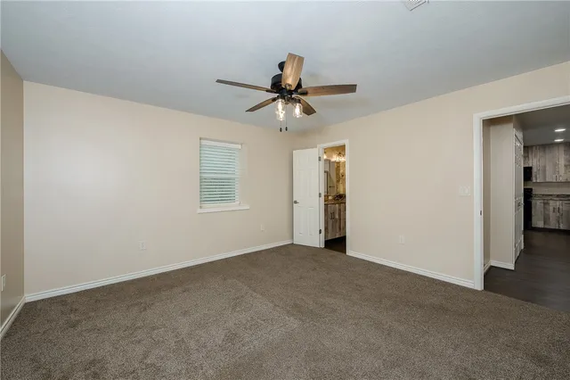 a view of a room with a ceiling fan and carpet