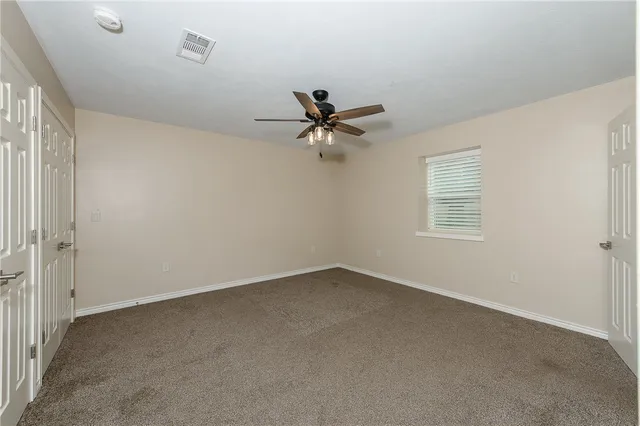 an empty room with a window and a ceiling fan