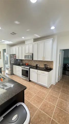 a large kitchen with granite countertop a large counter top a sink a stove a dining table and chairs