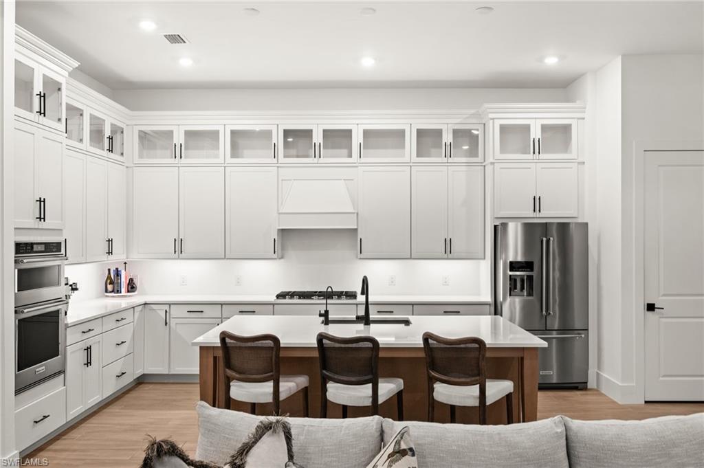 9565 Caymas Terrace Naples, FL 34114 - Photo 15 of 47 a kitchen with stainless steel appliances granite countertop a stove top oven a sink a dining table and chairs with white cabinets