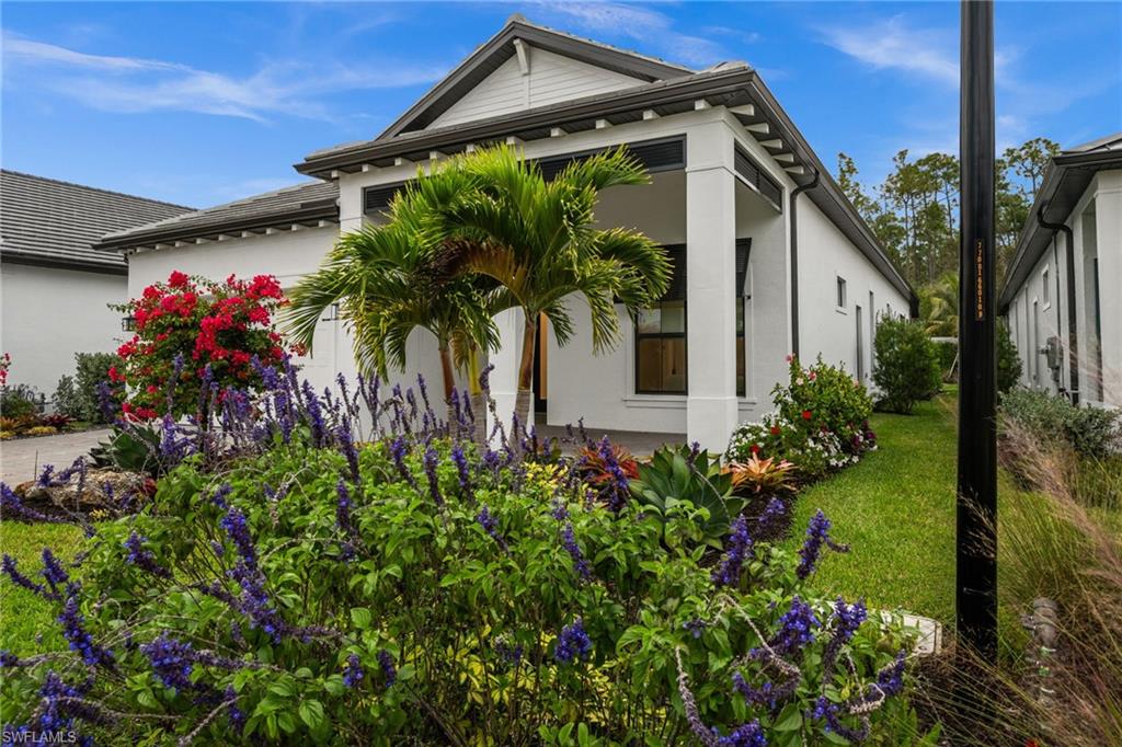 9565 Caymas Terrace Naples, FL 34114 - Photo 4 of 47 a front view of a house with a big yard and a fountain