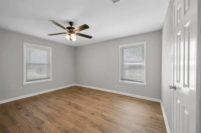 a view of an empty room with a window and wooden floor