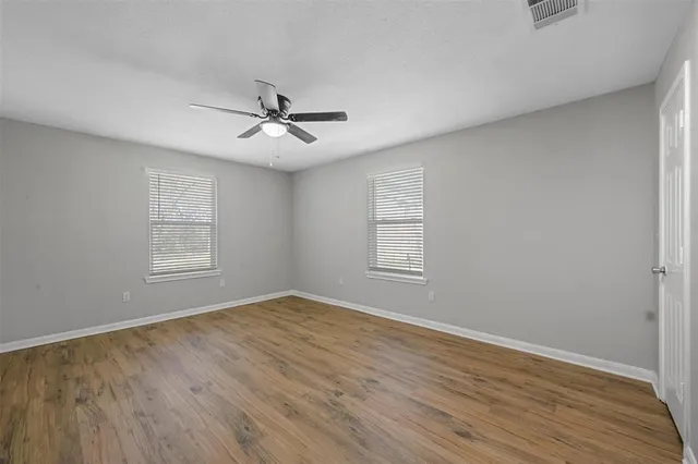 a view of empty room with wooden floor and fan