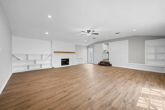 a view of empty room with wooden floor and fireplace