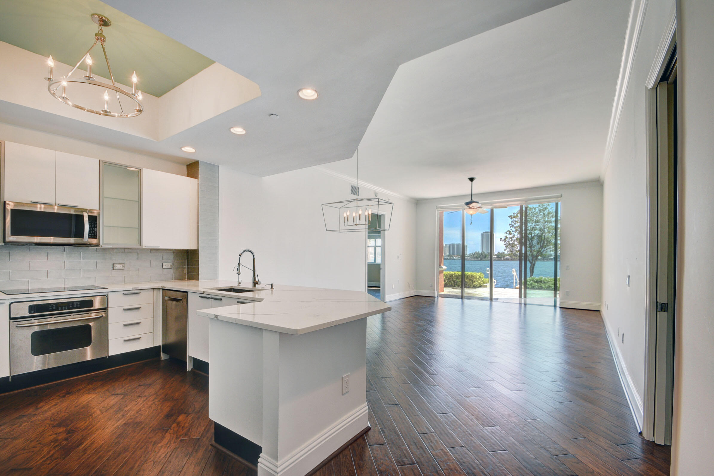 2640 Lake Shore Drive, Unit 115 Riviera Beach, FL 33404 - Photo 13 of 59 a kitchen with stainless steel appliances granite countertop a stove and a wooden floors