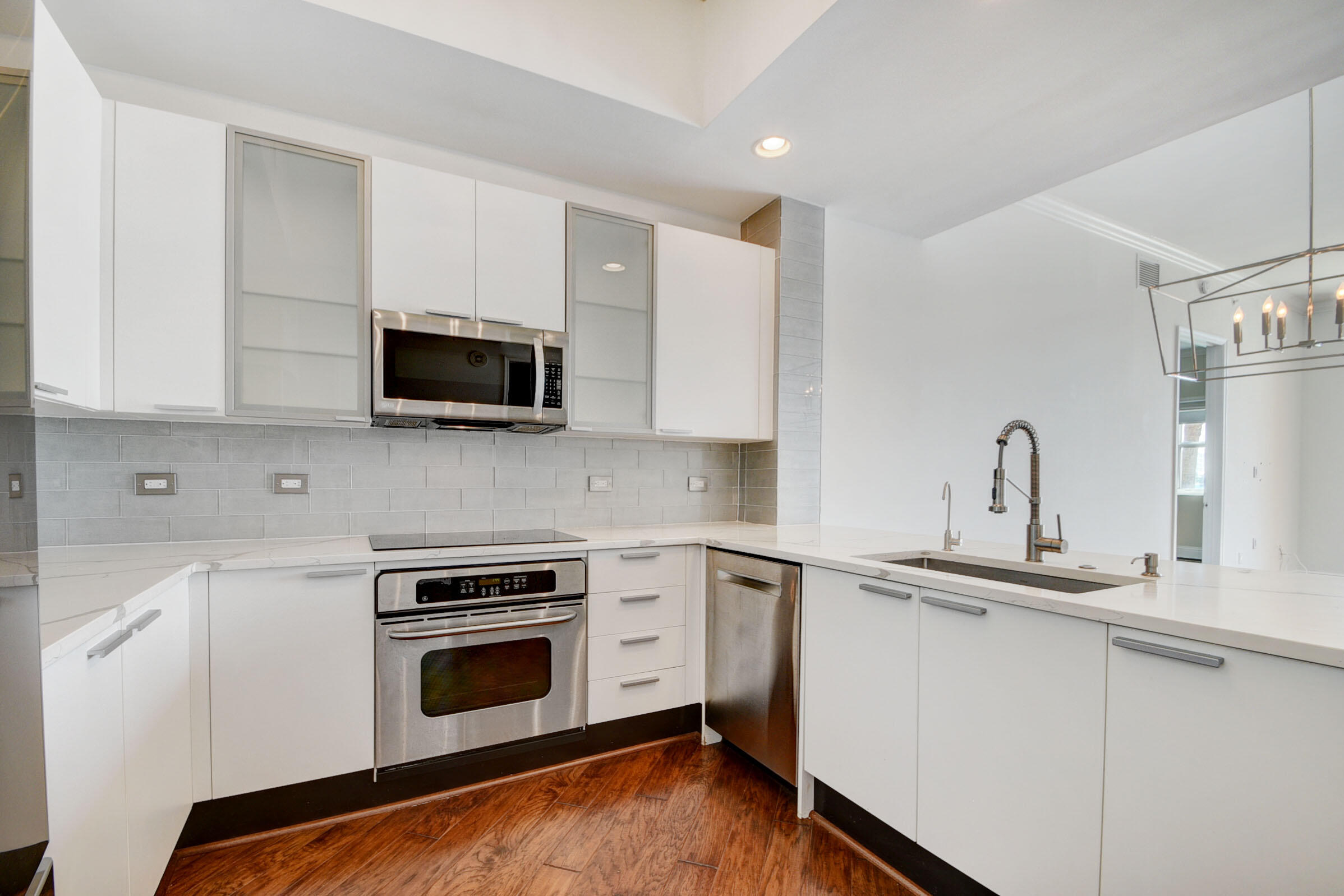 2640 Lake Shore Drive, Unit 115 Riviera Beach, FL 33404 - Photo 24 of 59 a kitchen with stainless steel appliances granite countertop a sink a stove top oven and white cabinets