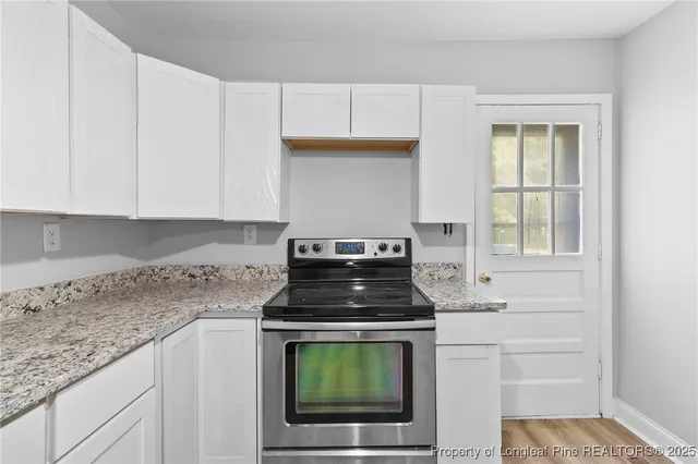 a kitchen with granite countertop white cabinets and stainless steel appliances