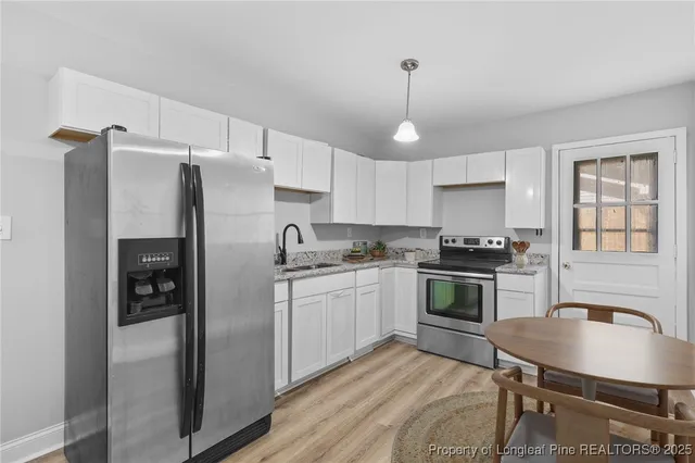 a kitchen with stainless steel appliances a refrigerator a stove a sink dishwasher a stove and white cabinets with wooden floor