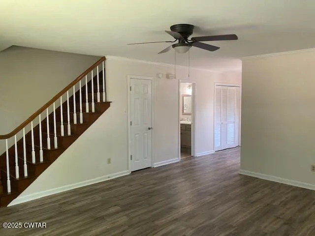 a view of an empty room with wooden floor and a ceiling fan