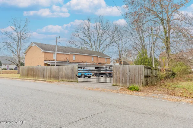 a view of a back yard of the house and cars parked on road