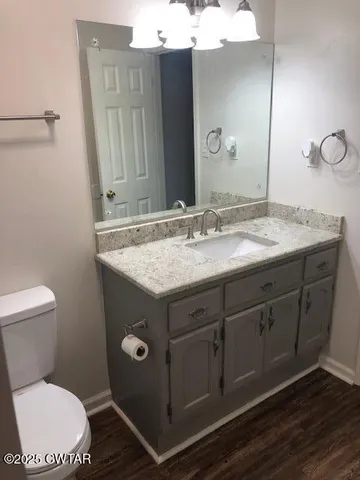 a bathroom with a granite countertop toilet sink and mirror