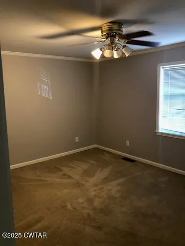 a view of an empty room with a chandelier fan