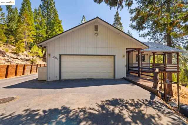 a view of a small house with wooden fence and large tree