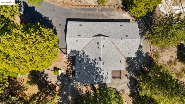an aerial view of residential house with outdoor space and trees all around