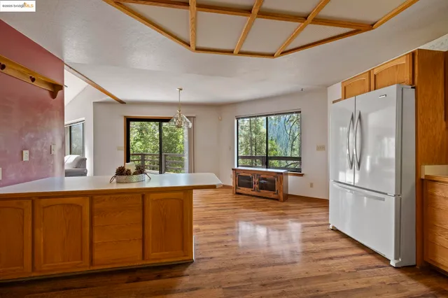 a living room with stainless steel appliances granite countertop a refrigerator and wooden floor