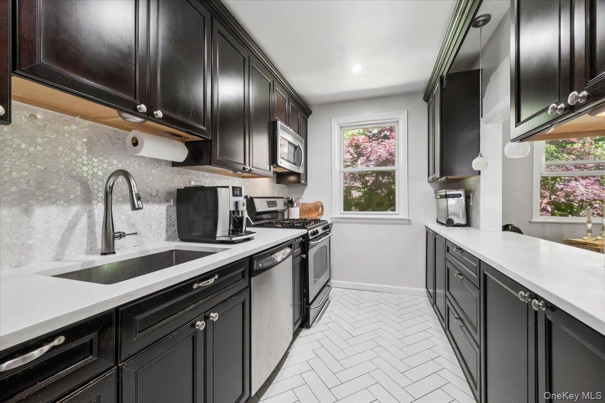 51 Avon Circle, Unit D Rye Brook, NY 10573 - Photo 3 of 30 Renovated kitchen with stainless steel appliances, tons of cabinets, attractive tile backsplash and white quartzite countertops.