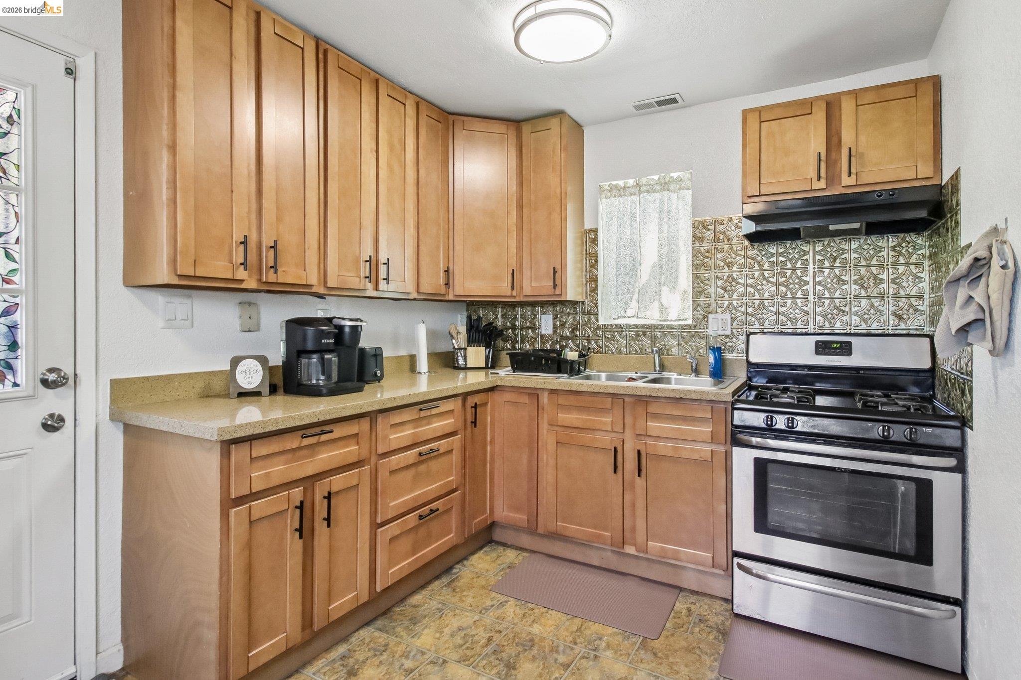 874 Pine Street Oakland, CA 94607 - Photo 9 of 39 Kitchen featuring a stainless steel gas range, wood cabinetry, light-toned countertops, and a patterned tile backsplash