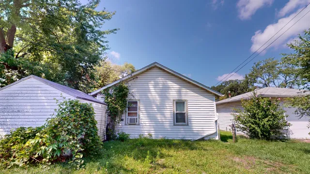 a view of a house with a yard plants and large tree