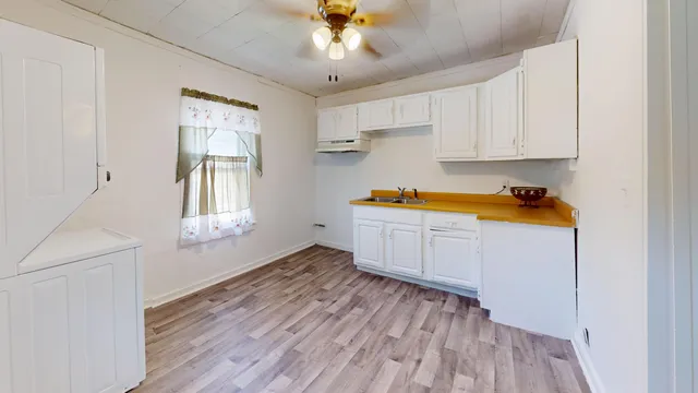 a kitchen with stainless steel appliances granite countertop a sink dishwasher a refrigerator with white cabinets and wooden floor