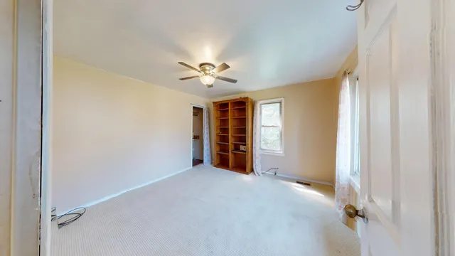 a view of a livingroom with a chandelier fan and windows