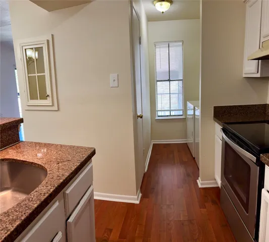 a kitchen with granite countertop a sink a stove and wooden floor