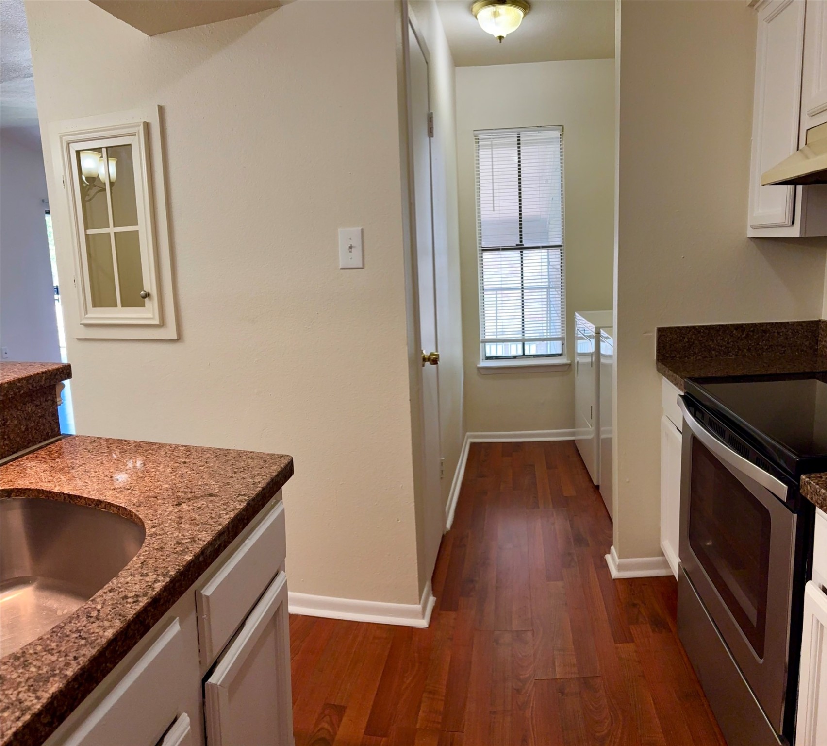 17331 Red Oak Drive, Unit 38 Houston, TX 77090 - Photo 11 of 19 a kitchen with granite countertop a sink a stove and wooden floor