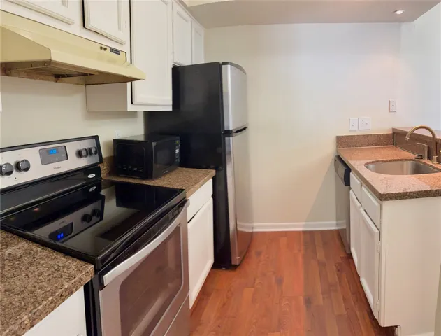 a kitchen that has a sink and a stove with wooden floor
