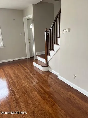 a view of a hallway with wooden floor and staircase