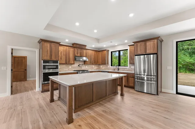a kitchen with stainless steel appliances kitchen island granite countertop a stove a sink a refrigerator and cabinets