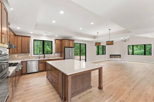 a view of a kitchen with stainless steel appliances granite countertop a stove and a wooden floor