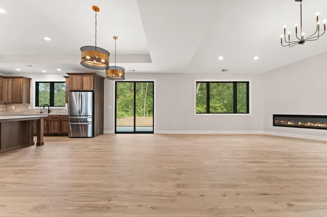 an empty room with windows wooden floor kitchen view and windows