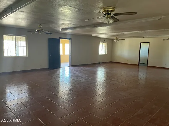 an empty room with windows and ceiling fan