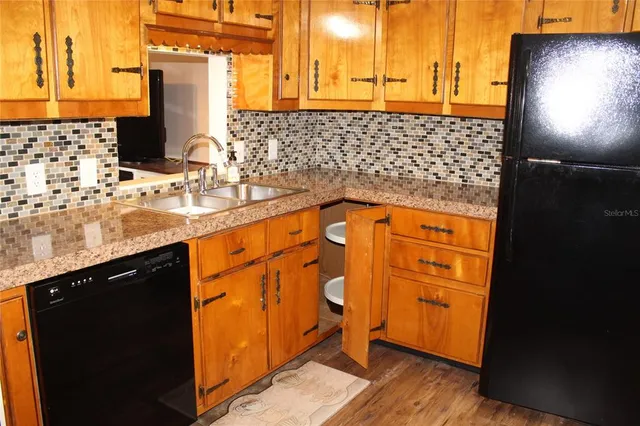 a kitchen with stainless steel appliances granite countertop a stove a sink a microwave a dining table and chairs with wooden floor