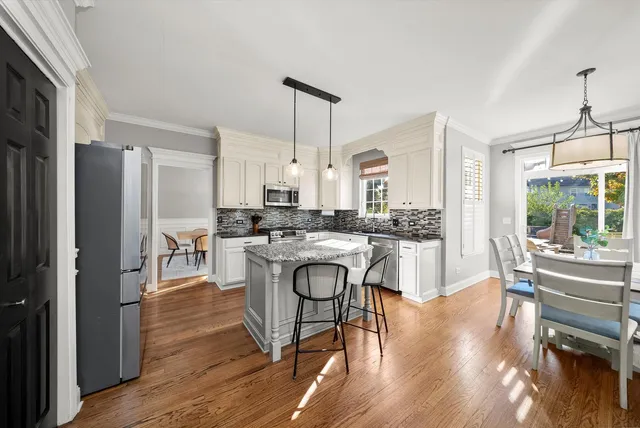 a kitchen with kitchen island granite countertop a table chairs refrigerator and cabinets