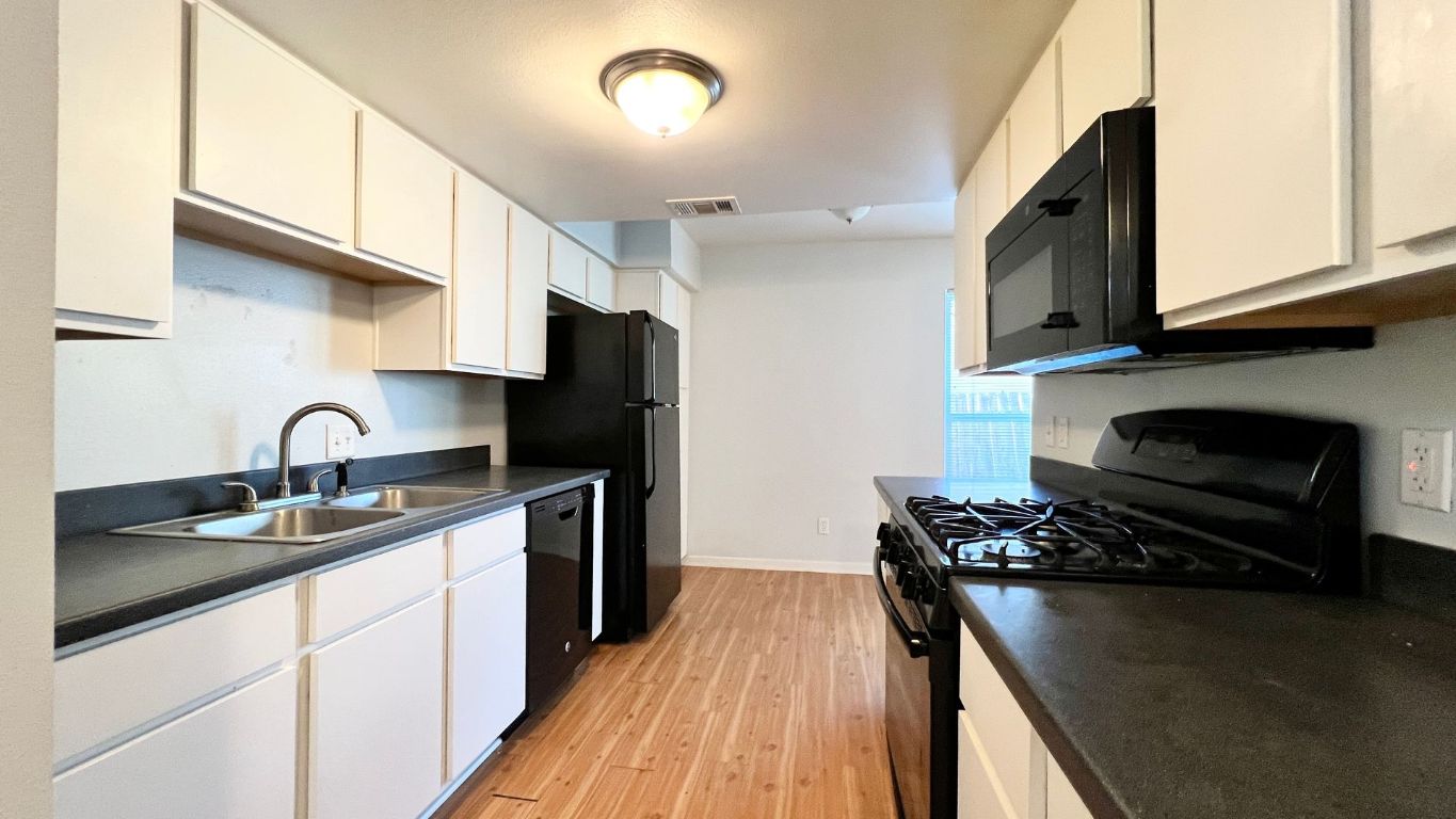 2301 Ohlen Road, Unit 103 Austin, TX 78757 - Photo 3 of 12 Kitchen featuring black appliances, dark countertops, light wood-type flooring, and white cabinetry
