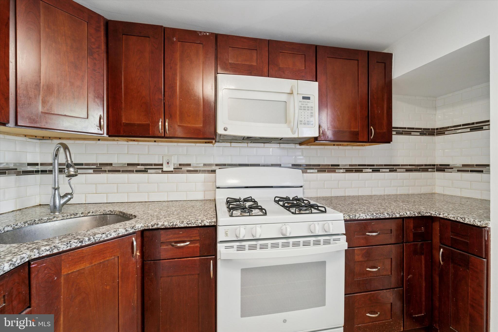 3052 Aramingo Avenue Philadelphia, PA 19134 - Photo 11 of 24 a kitchen with granite countertop cabinets and white stove