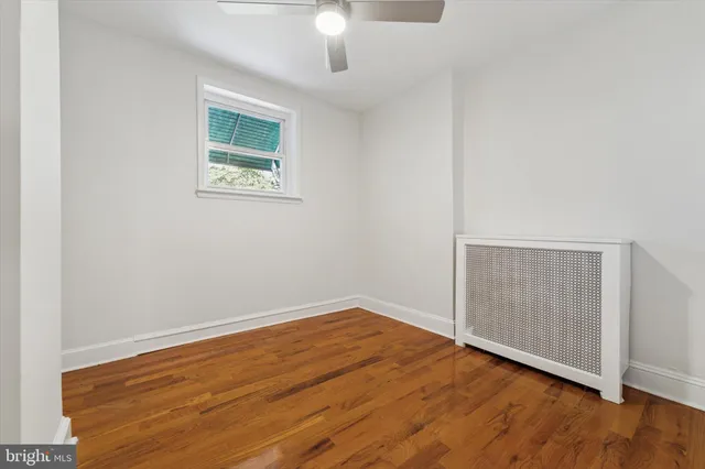 an empty room with wooden floor chandelier fan and windows