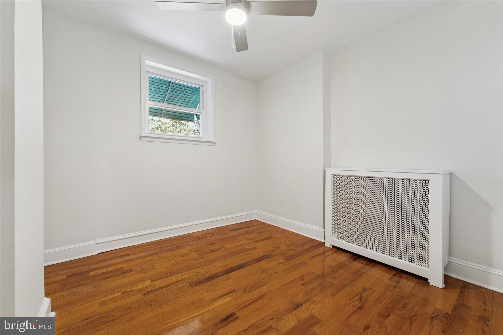 3052 Aramingo Avenue Philadelphia, PA 19134 - Photo 12 of 24 an empty room with wooden floor chandelier fan and windows